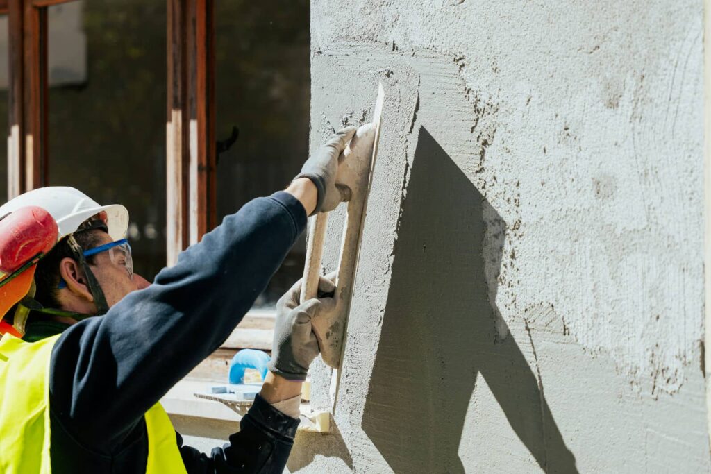Costruire casa da zero: muratore che intonaca il muro