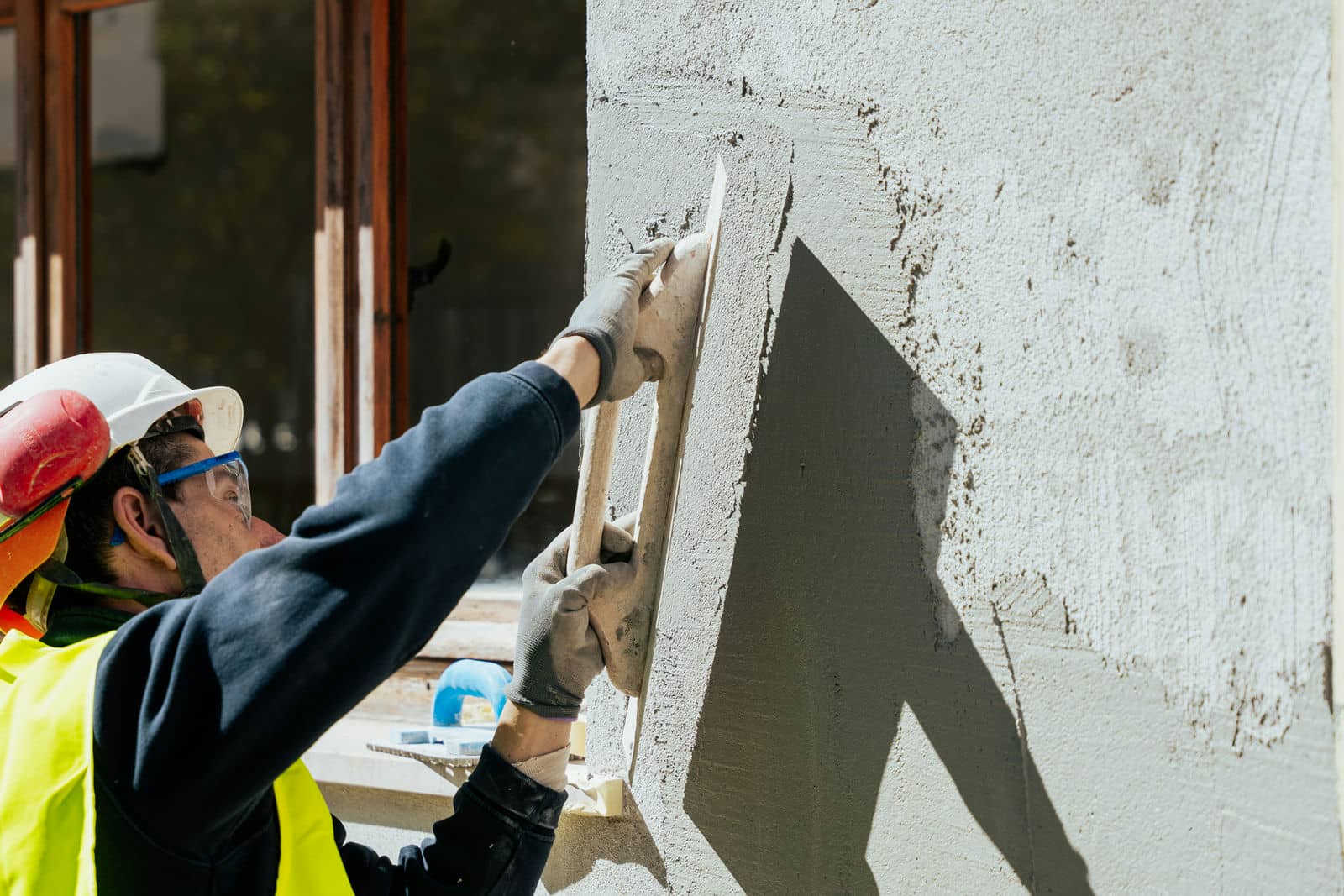 Costruire casa da zero: muratore che intonaca il muro
